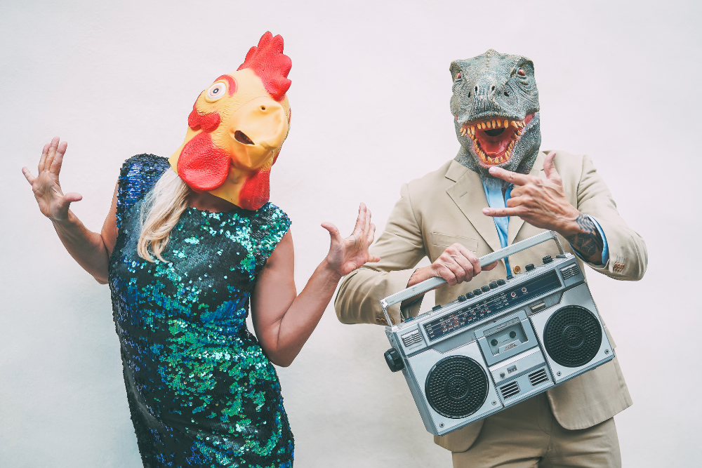 Wedding guests in dinosaur and chicken masks having fun, showing unique wedding entertainment ideas.