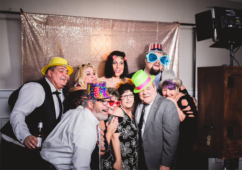 Disappearing Wedding Trends - Group Of People Taking Photo Booth Pictures With Props