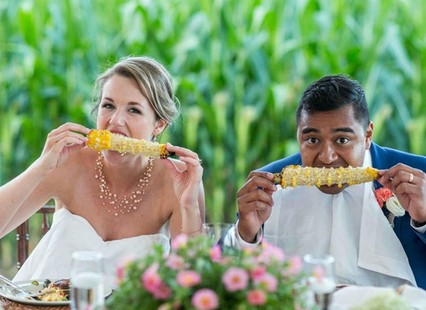 Bride And Groom Eating Corn On The Cob Outside At Wedding Celebration