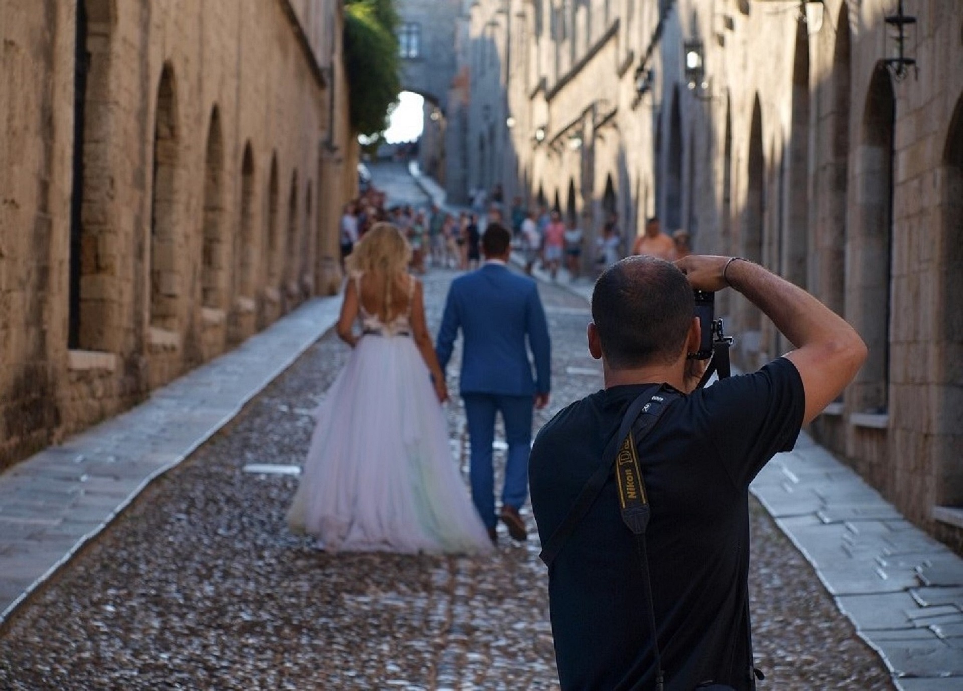 Wedding Photographer Taking Photo Of Bride And Groom In Small Street In Europe